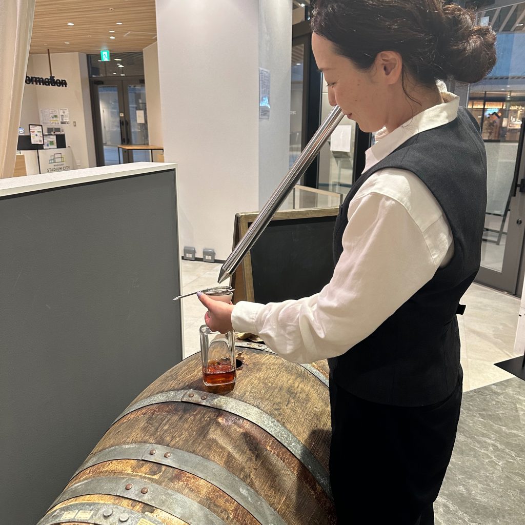 樽の前で飲み物を注ぐ店の人