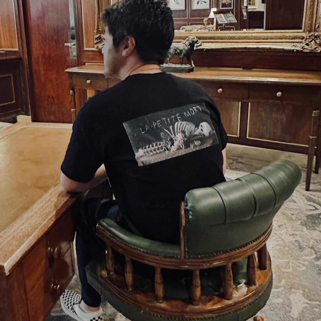 椅子に座ってTシャツのプリントを見せる男性